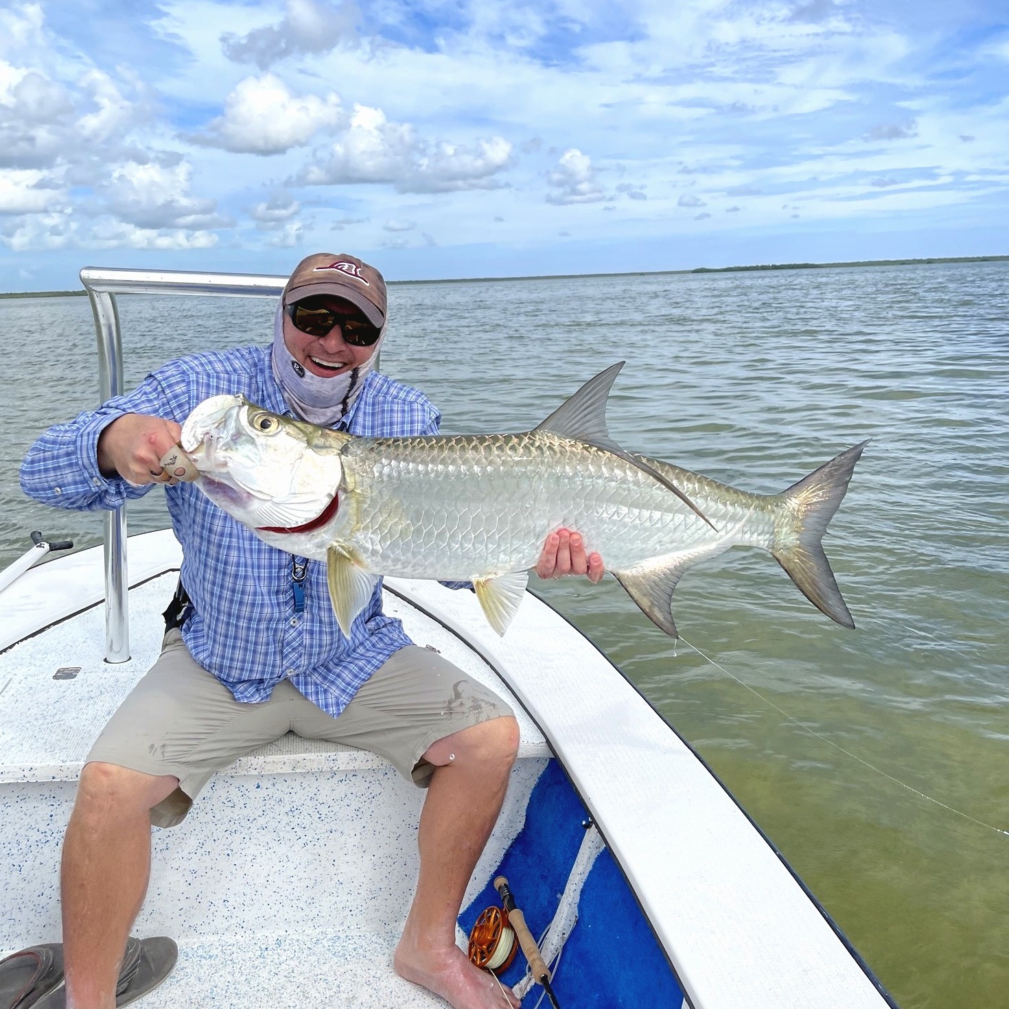 Brandon Fries on a skiff, holding a silver Atlantic tarpon
